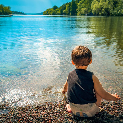 Enfant devant un lac, jouant sur le bord